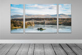 Canvas Wrap Triptych Wall Art - Blue Skies at Menai Bridge, Anglesey - North Wales. A Panoramic image of Menai Bridge with the blue sky reflecting into the water of the Menai Straits. Clouds sit in the sky above the hills behind the bridge and the trees surrounding are vibrant green colours. Image split into 3 panels to make a triptych image. Smart Imaging & Framing Landscape Photography