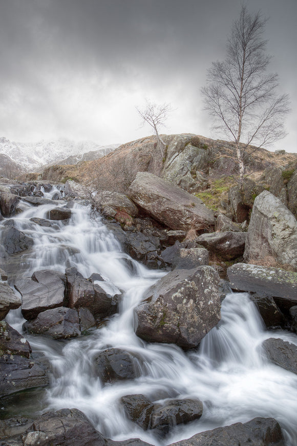 Rhaeadr Idwal is the waterfall on the path leading from Llyn Ogwen towards Cwm Idwal. A cold Winter's day with grey skies and snow covered mountains as the water cascades over the rocks