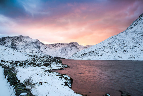 Sunset over Snowdonia. Beautiful pastel purples & oranges fill the sky above the snow covered mountains surrounding Llyn Ogwen in Snowdonia, North Wales. Smart Imaging & Framing Landscape Photography