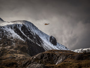 RAF Mountain rescue in Snowdonia. The now retired, yellow Seaking helicopter flies around the snow covered mountains surrounding llyn Idwal