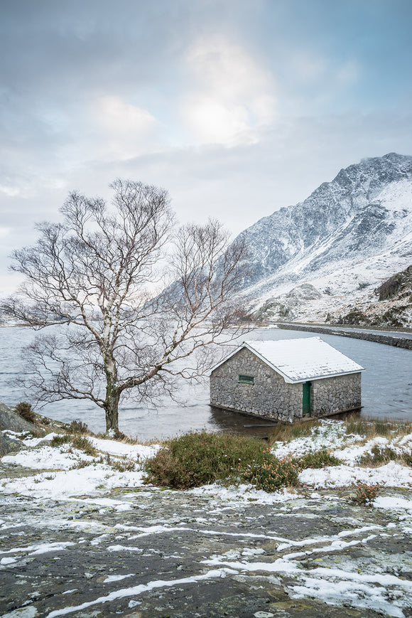A Winter's day at Llyn Ogwen. A more unusual upright landscape showing blue cloudy skies above llyn ogwen and a small amount of snow on the ground. Snowdonia National Park, North Wales