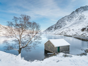 Snowfall at Llyn Ogwen - A crisp, Winter's day in Snowdonia National Park. White snow lays all around while the blue sky above reflects on the frozen surface of Llyn Ogwen