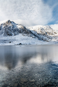 Llyn Idwal, Broken Reflections, Snowdonia - North Wales. A Winter scene at Llyn Idwal where the snow covered mountains are reflecting in the frozen surface of the lake below. The ice has broken around the edges of the lake