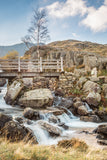 The Bridge across Rhaeadr Idwal, Snowdonia. Beautiful blue skies above this popular waterfall in Snowdonia, North Wales. Water flows over the rocks below the wooden bridge that spans the falls
