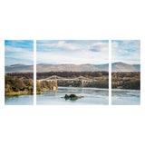 Canvas Wrap Triptych Wall Art - Blue Skies at Menai Bridge, Anglesey - North Wales. A Panoramic image of Menai Bridge with the blue sky reflecting into the water of the Menai Straits. Clouds sit in the sky above the hills behind the bridge and the trees surrounding are vibrant green colours. Image split into 3 panels to make a triptych image. Smart Imaging & Framing Landscape Photography